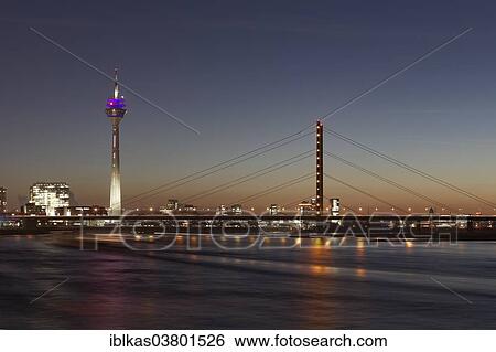 Stock Photograph - "Skyline with Rheinturm tower, """"Stadttor"""" high-rise building and Rheinkniebrucke bridge at twilight, Dusseldorf, North Rhine-Westphalia, Germany, Europe". Fotosearch