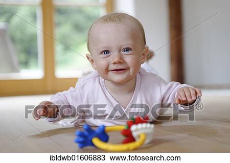 Stock Image - "Small baby, 4 months, lying on her belly, with teether". Fotosearch