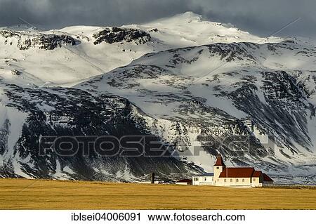 Stock Image - "Small chapel in front of tall, snow-covered mountains, Snaefellsnes Peninsula, Iceland, Europe". Fotosearch