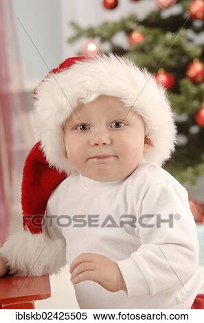Small child with a Santa hat sitting in front of a Christmas tree View Large Photo Image Stock Photography - Small child with a Santa hat sitting in front of a Christmas tree. Fotosearch