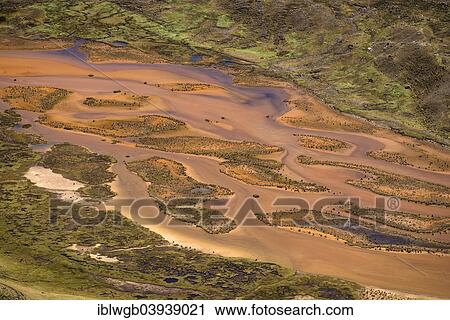 Stock Image - "Small meandering river carries large quantities of sediments, dissolved clay, sand and clay in its water, Cordillera Huayhuash range, Andes, northern Peru, Peru, South America". Fotosearch