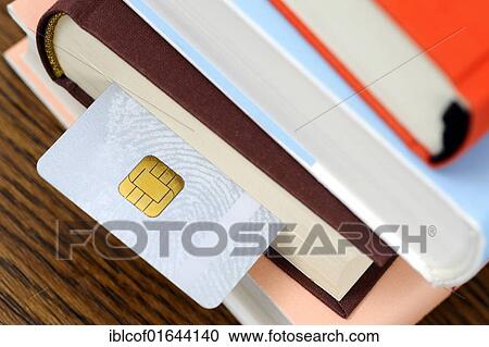 Stock Image - "Smart card in a stack of books, symbolic image for an educational smart card". Fotosearch
