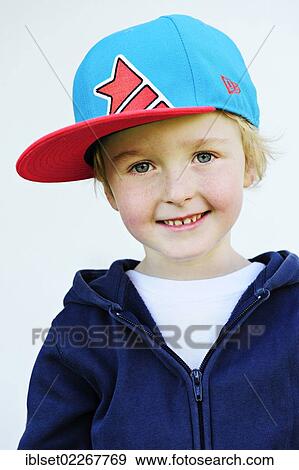 Stock Photo - "Smiling 5-year-old boy wearing a baseball cap, portrait". Fotosearch