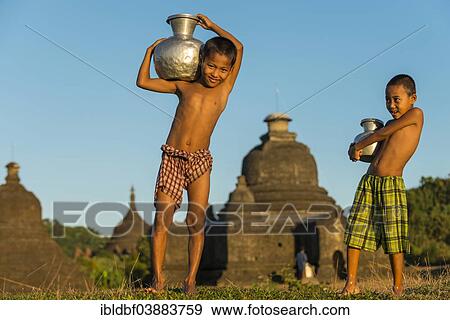"Smiling boys carrying water in front of a pagoda or a temple, Mrauk U, Sittwe District, Rakhine State, Myanmar, Asia" View Large Photo Image Stock Photo - "Smiling boys carrying water in front of a pagoda or a temple, Mrauk U, Sittwe District, Rakhine State, Myanmar, Asia". Fotosearch