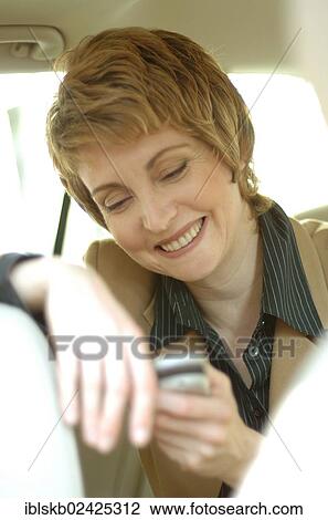 Smiling business woman with a mobile phone in a car View Large Photo Image Stock Image - Smiling business woman with a mobile phone in a car. Fotosearch