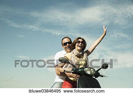 Stock Photography - "Smiling couple driving with the scooter, Mannheim, Baden-Wurttemberg, Germany, Europe". Fotosearch