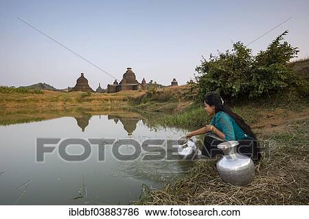"Smiling girl drawing water from a water hole with a vessel made of aluminium, Laymyetnta Pagoda or Temple, Mrauk U, Sittwe District, Rakhine State, Myanmar, Asia" View Large Photo Image Stock Photograph - "Smiling girl drawing water from a water hole with a vessel made of aluminium, Laymyetnta Pagoda or Temple, Mrauk U, Sittwe District, Rakhine State, Myanmar, Asia". Fotosearch