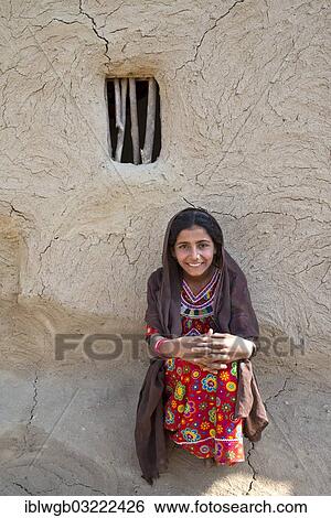 "Smiling girl wearing a headscarf and traditional clothing sitting in front of a house wall with a window opening, Rann of Kutch, Gujarat, India, Asia" View Large Photo Image Stock Photograph - "Smiling girl wearing a headscarf and traditional clothing sitting in front of a house wall with a window opening, Rann of Kutch, Gujarat, India, Asia". Fotosearch