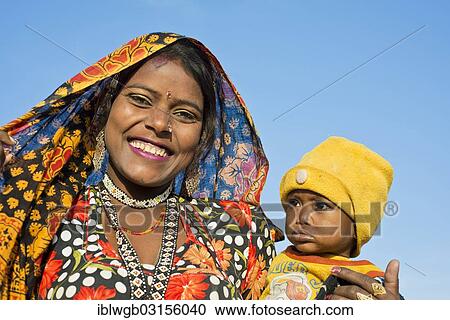 "Smiling Indian women with a colourful scarf holding a small child in her arms, portrait, Pushkar, Rajasthan, India, Asia" View Large Photo Image Stock Image - "Smiling Indian women with a colourful scarf holding a small child in her arms, portrait, Pushkar, Rajasthan, India, Asia". Fotosearch