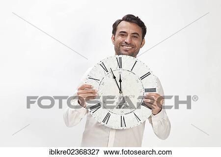 "Smiling man holding a clock at eleven fifty-five, almost high noon" View Large Photo Image Stock Photo - "Smiling man holding a clock at eleven fifty-five, almost high noon". Fotosearch