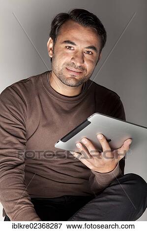 Smiling man holding an iPad View Large Photo Image Stock Photo - Smiling man holding an iPad. Fotosearch