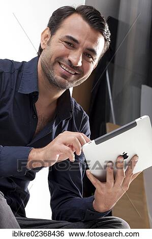 Smiling man holding an iPad View Large Photo Image Stock Photograph - Smiling man holding an iPad. Fotosearch