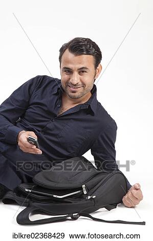 Stock Photo - "Smiling man with a backpack, an iPad and a mobile phone". Fotosearch