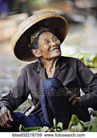 Stock Photo - "Smiling old woman wearing a straw hat at the floating market, Damnoen Saduak, Thailand, Southeast Asia, Asia". Fotosearch