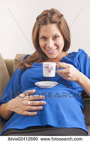 Stock Image - Smiling pregnant woman drinking coffee. Fotosearch