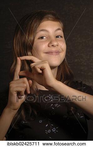 Stock Image - Smiling teenage girl making sign language. Fotosearch