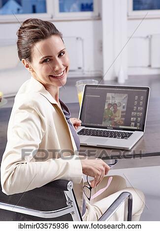 "Smiling woman sitting in front of a laptop, Munich, Upper Bavaria, Bavaria, Germany, Europe" View Large Photo Image Stock Photograph - "Smiling woman sitting in front of a laptop, Munich, Upper Bavaria, Bavaria, Germany, Europe". Fotosearch