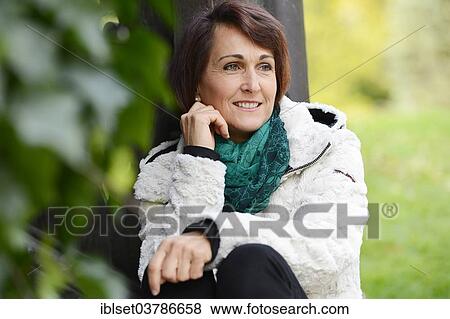 Stock Photo - Smiling woman sitting outdoors. Fotosearch