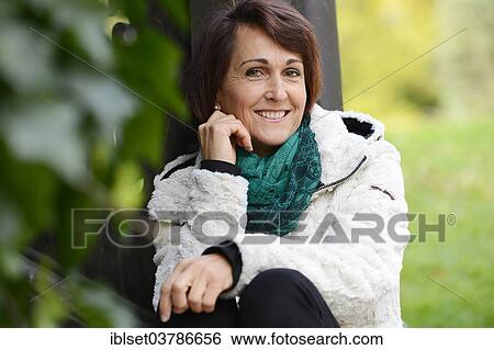 Stock Photograph - Smiling woman sitting outdoors. Fotosearch