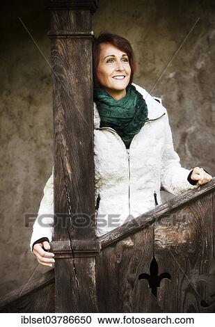 Smiling woman standing at a wooden railing View Large Photo Image Stock Image - Smiling woman standing at a wooden railing. Fotosearch