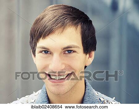 "Smiling young man wearing a studded denim jacket, portrait" View Large Photo Image Picture - "Smiling young man wearing a studded denim jacket, portrait". Fotosearch
