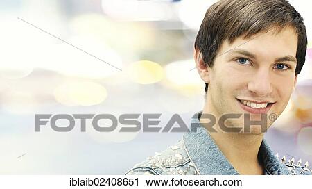 Stock Image - "Smiling young man wearing a studded denim jacket, portrait". Fotosearch