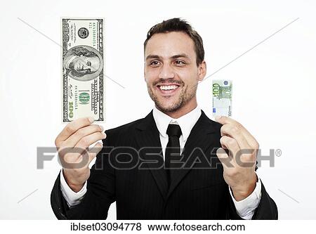 "Smiling young man wearing a suit holding a large 100 dollar bill and a small 100 euro banknote, Austria, Europe" View Large Photo Image Stock Photo - "Smiling young man wearing a suit holding a large 100 dollar bill and a small 100 euro banknote, Austria, Europe". Fotosearch