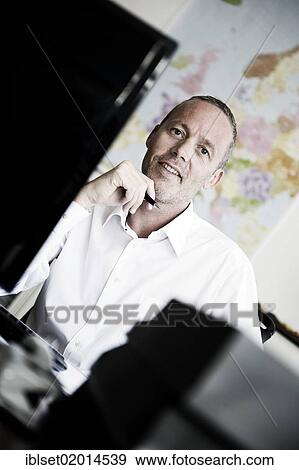 "Smiling young man with a pen in his hand, sitting at a computer in an office, world map at the back" View Large Photo Image Stock Photo - "Smiling young man with a pen in his hand, sitting at a computer in an office, world map at the back". Fotosearch