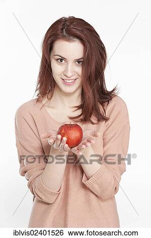Stock Photograph - Smiling young woman holding apple. Fotosearch