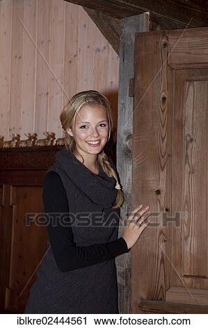 Smiling young woman leaning against an old door View Large Photo Image Stock Image - Smiling young woman leaning against an old door. Fotosearch