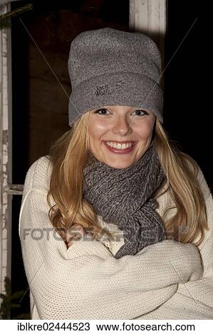 Smiling young woman wearing a cap and a scarf standing in front of a hiking hut View Large Photo Image Stock Image - Smiling young woman wearing a cap and a scarf standing in front of a hiking hut. Fotosearch