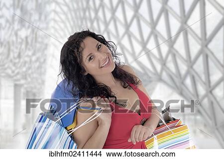 Picture - "Smiling young woman with colourful shopping bags in a modern department store, Berlin, Germany, Europe". Fotosearch