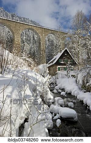 Stock Image - "Snow-covered creek with a Black Forest house and a railway bridge, Ravenna gorge, Black Forest, Baden-Wurttemberg, Germany, Europe". Fotosearch
