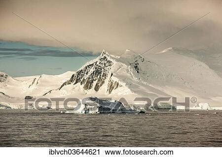 Stock Image - "Snow-covered rocks, icebergs, in the morning light, Antarctic Peninsula, Antarctica". Fotosearch