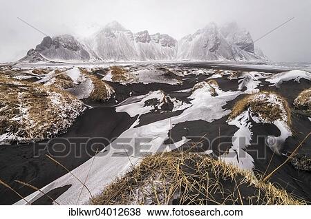 Stock Photo - "Snow on black sand dunes in front of Vestrahorn mountain in winter, fog, Stokksnes, Hofn, Iceland, Europe". Fotosearch