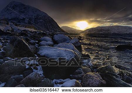 Stock Photo - "Snowy stoneson the fjord at sunrise, Tromso, â€ªTroms, Northern Norway, Norway, Europe". Fotosearch