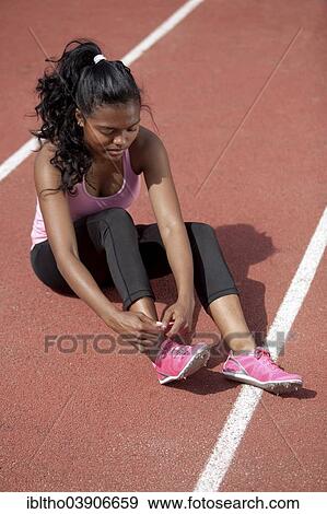 "Sporty young woman, sitting on race track, tightening her running shoes" View Large Photo Image Stock Photo - "Sporty young woman, sitting on race track, tightening her running shoes". Fotosearch