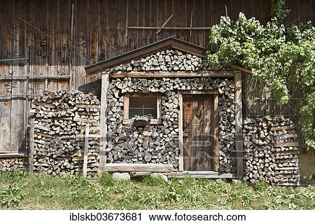 Stack Of Firewood In The Shape Of A Log Cabin With A Rustic Front