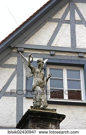 Stock Photo - "Statue of an angel in front of a half-timbered house, Kirchplatz, Biberach, Upper Swabia, Baden-Wuerttemberg, Germany, Europe". Fotosearch