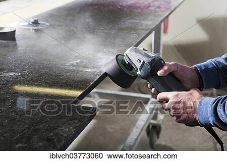 Stock Image - Stone slab is ground down with a grinder. Fotosearch