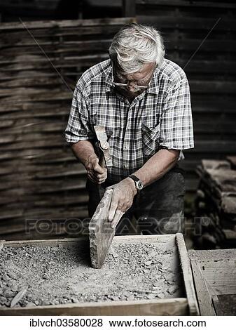 Stock Photo - "Stonemason working on a stone slab with a hammer, Reith im Alpbachtal, Kufstein District, North Tirol, Tirol, Austria, Europe". Fotosearch