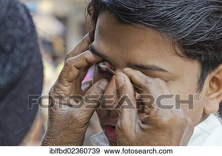 Stock Photo - "Street eye cleaner with a customer in the streets of Kolkata, India, Asia". Fotosearch