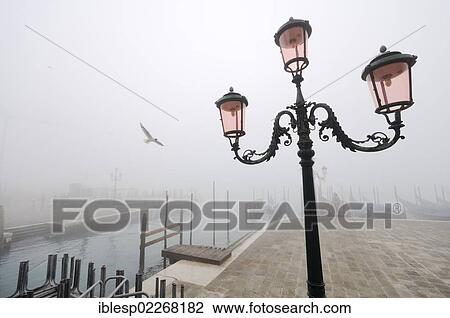 Stock Image - "Street lamp and gondolas in the fog, Molo della Piazzetta, St. Mark's Square, Piazza San Marco, Venice, Venezia, Veneto, Italy, Europe". Fotosearch