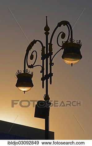 Stock Photo - "Street lamp back-lit by the setting sun at the Corniche of Muttrah, Muttrah, Muscat Governorate (Capital Area, Oman, Asia". Fotosearch