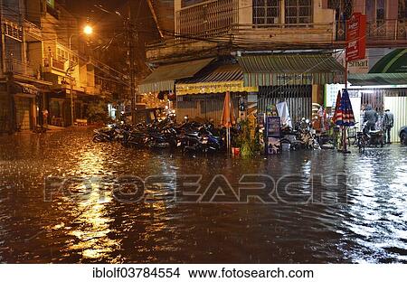 Picture - "Street scene with a flooded road during heavy monsoon rain at night, city centre, Phnom Penh, Cambodia, Asia". Fotosearch