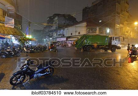 Stock Image - "Street scene with a flooded road during heavy monsoon rain at night, city centre, Phnom Penh, Cambodia, Asia". Fotosearch