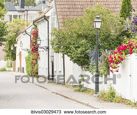 Stock Image - "Street with old residential houses and flowers, Vadstena, Ostergotland County, Sweden, Europe". Fotosearch
