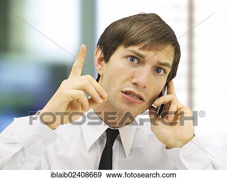 Stock Photo - "Stressed businessman speaking on his mobile phone, portrait, with an admonishing gesture, with a wagging finger". Fotosearch