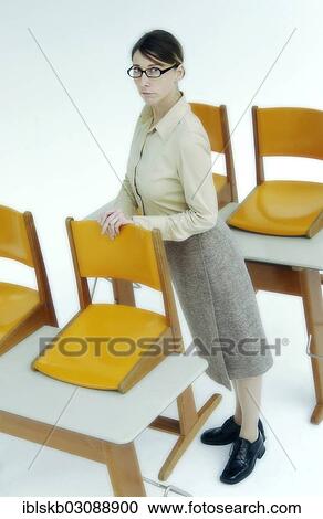 Strict female teacher standing at old school desks with orange chairs View Large Photo Image Stock Image - Strict female teacher standing at old school desks with orange chairs. Fotosearch