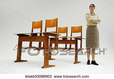 Strict Female Teacher Standing Next To Old School Desks With